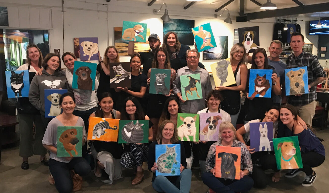 Man with a paintbrush painting a canvas of a woman